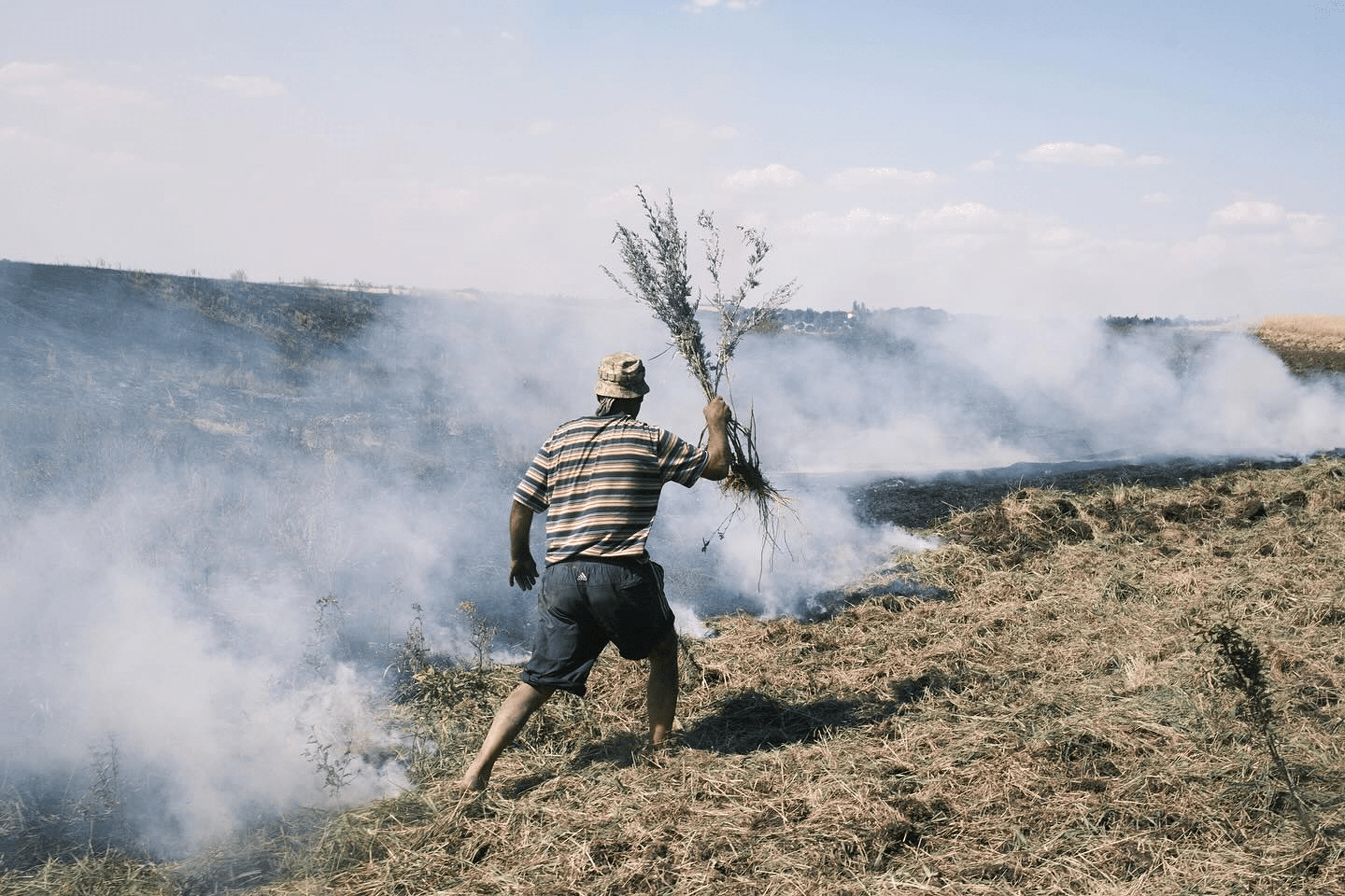 Wheat fields burn after shelling as local resident Enver, 46, helps to put out the fire. Nova Poltavka, Donetsk region, Ukraine.