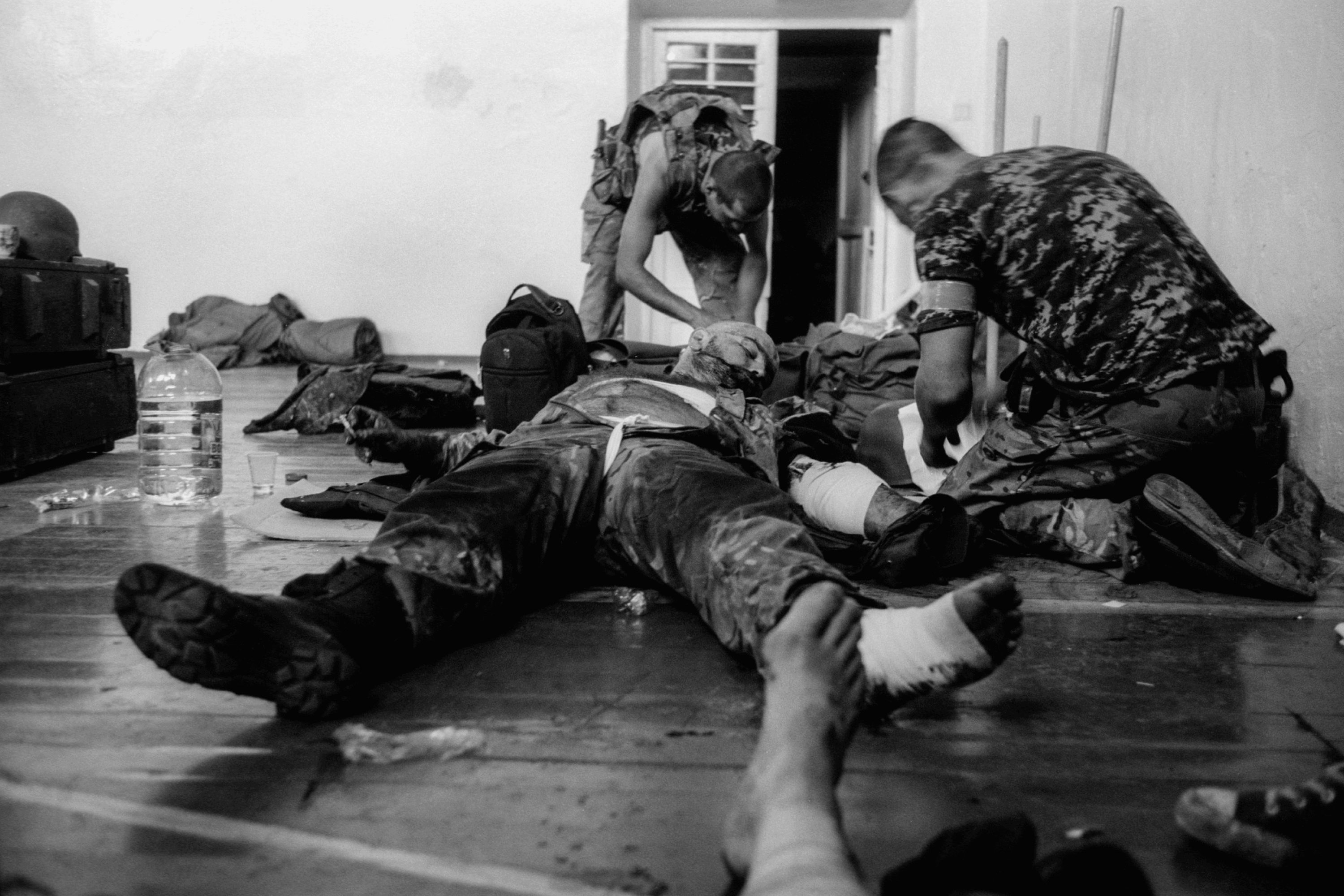 Comrades assist a fighter of the “Donbas” battalion who was wounded by shrapnel in Ilovaisk. Oleksandr Glyadyelov was also injured during this shelling. He took this photo after being wounded — his leg is visible in the foreground. 21 August, 2014.