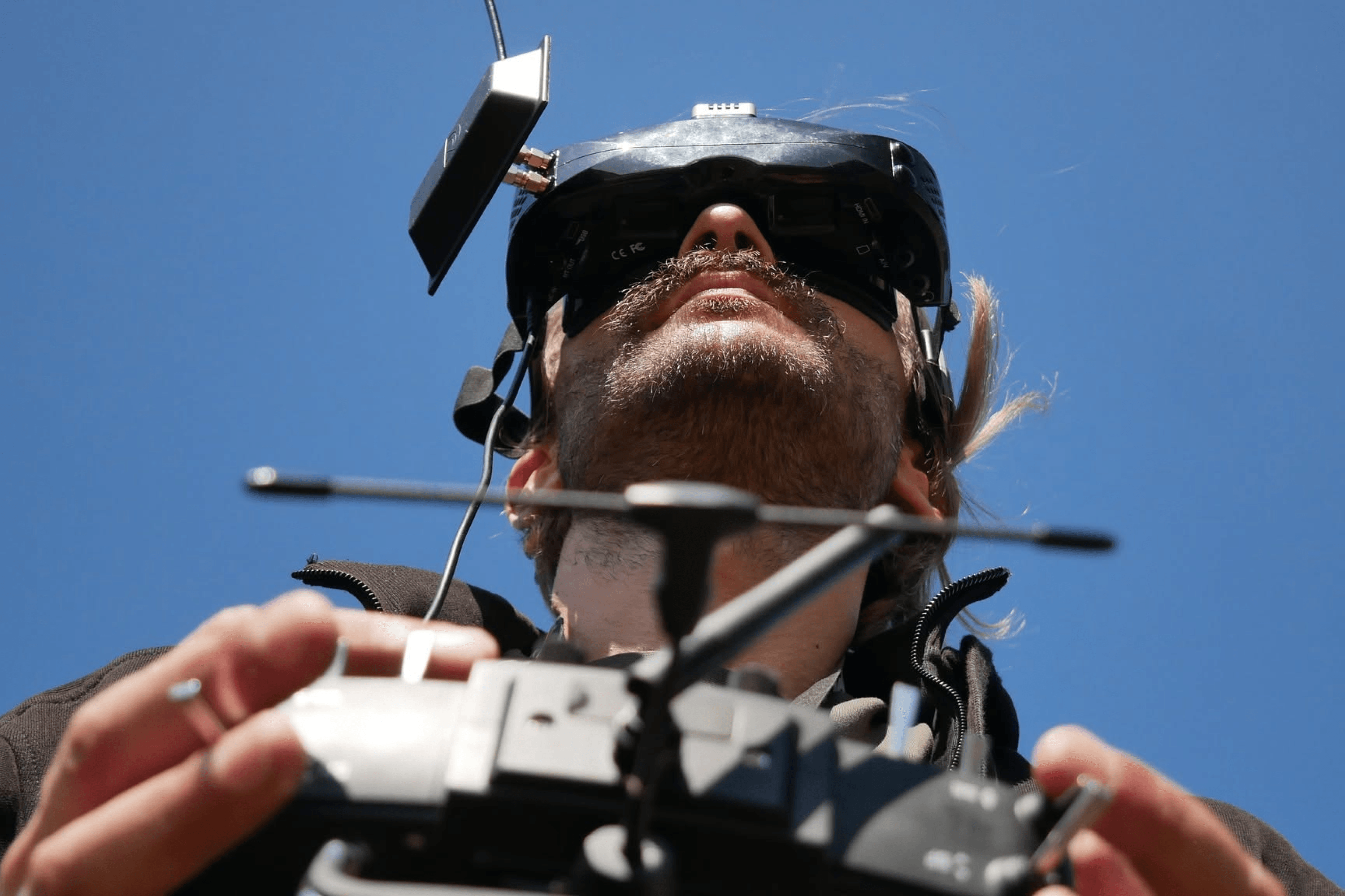 A participant in the Precision hackathon wearing FPV goggles and holding a drone controller. August 2024.