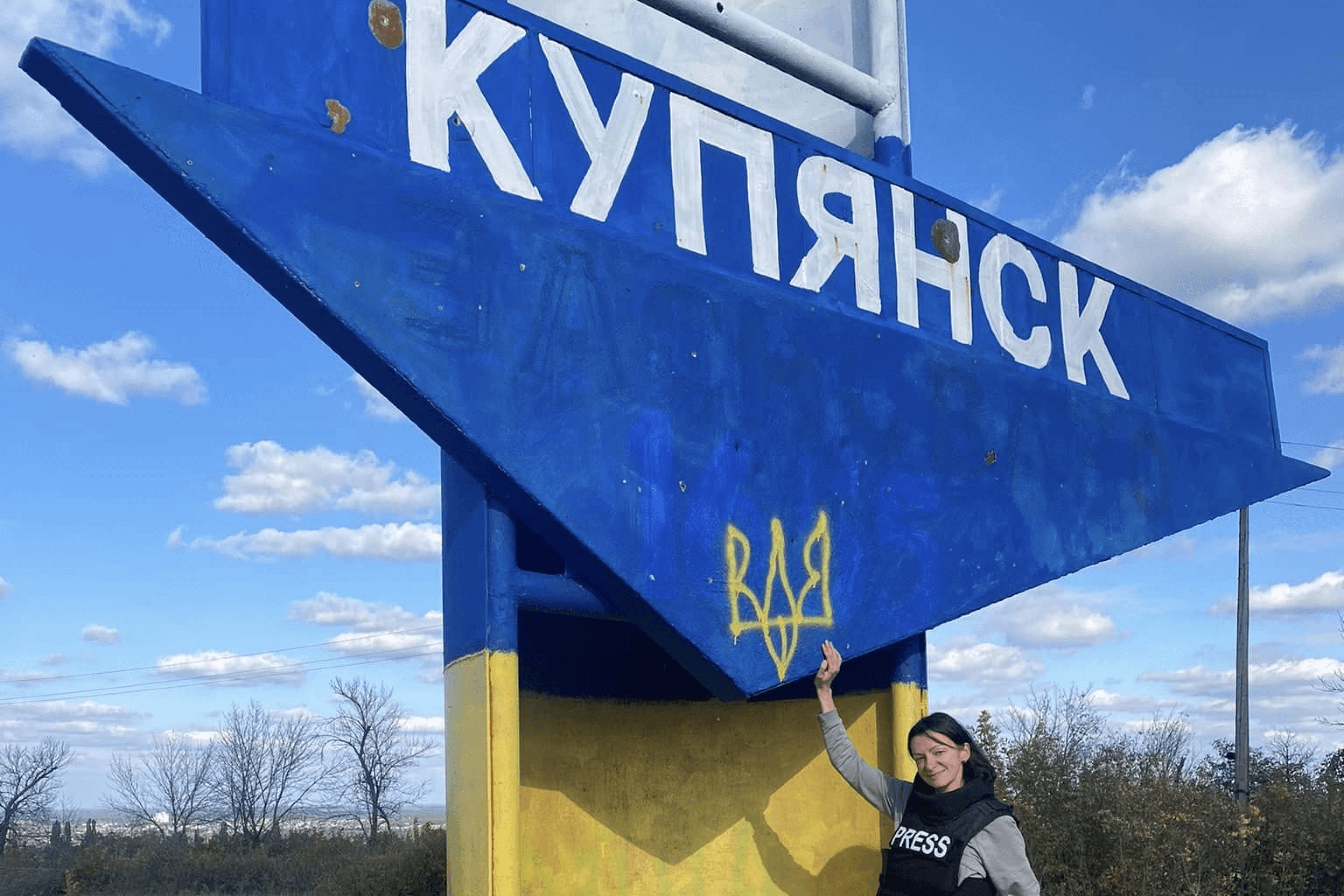 Journalist Kristina Berdynskykh by the entrance sign to Kupiansk, Kharkiv Oblast, after the city’s liberation. October 2022.