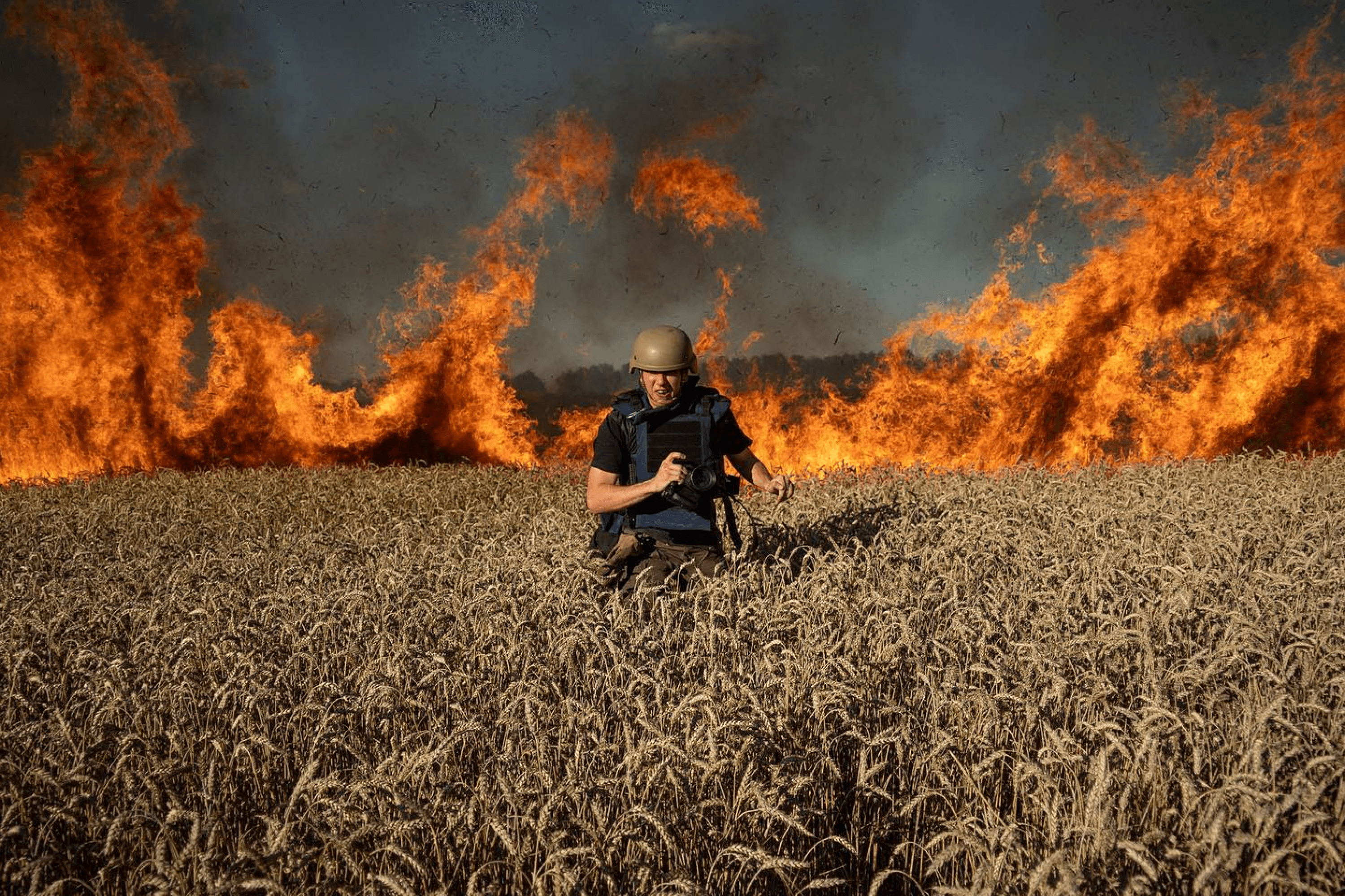 Photojournalist Evgeniy Maloletka runs from the fire in a burning wheat field after a Russian shelling, a few kilometers from the Ukrainian-Russian border in Kharkiv region, Ukraine. July 2022.