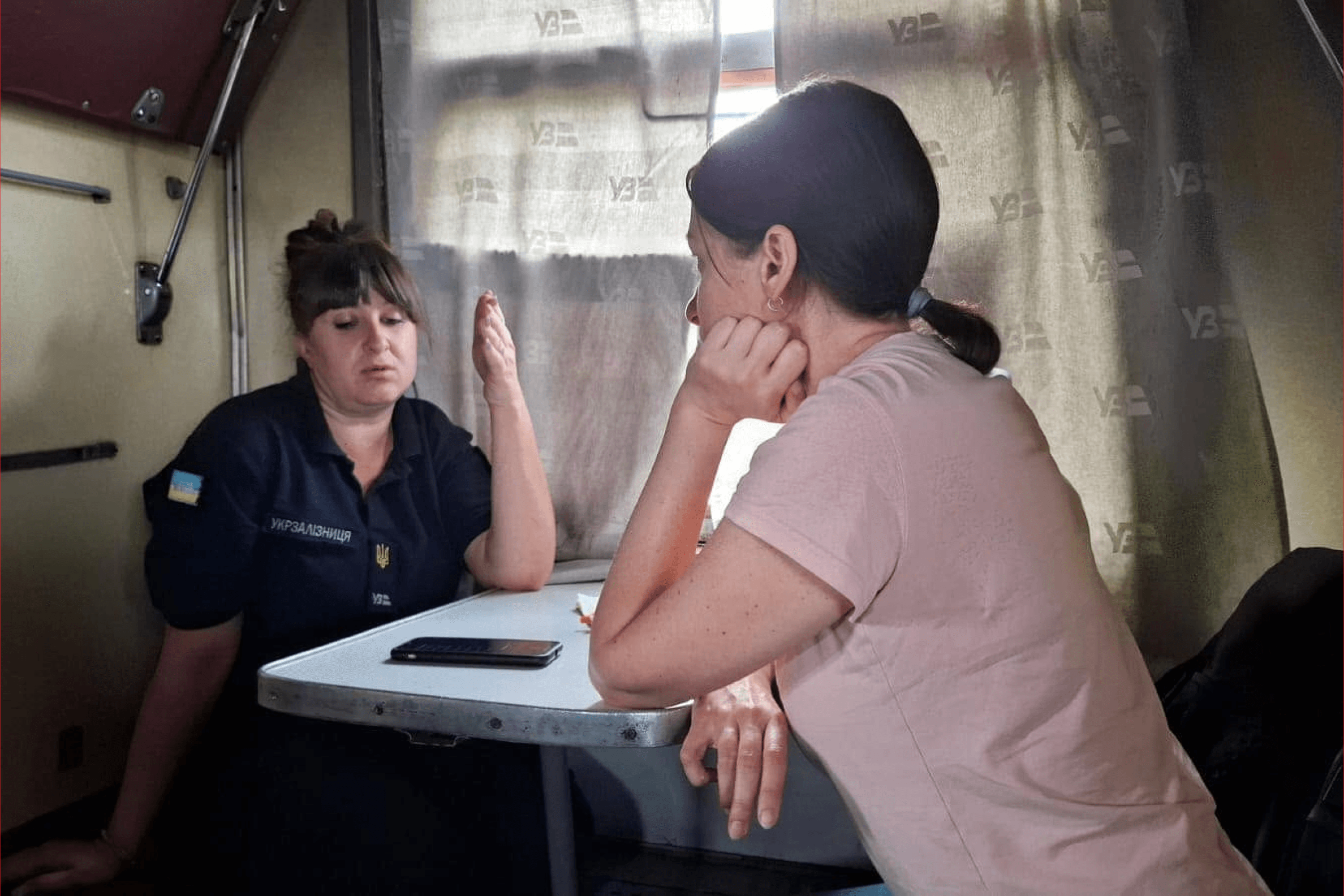 An evacuation train from Pokrovsk: journalist Kristina Berdynskykh speaks with a train conductor while reporting. Pokrovsk, Donetsk Oblast. September 2024.